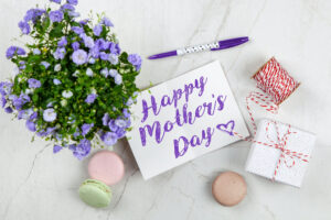 a mother's day card next to a bouquet of flowers and macaroons