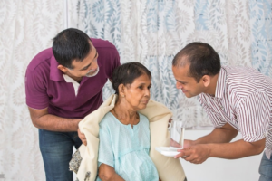 Two men offer their cancer-diagnosed mother a glass of water.