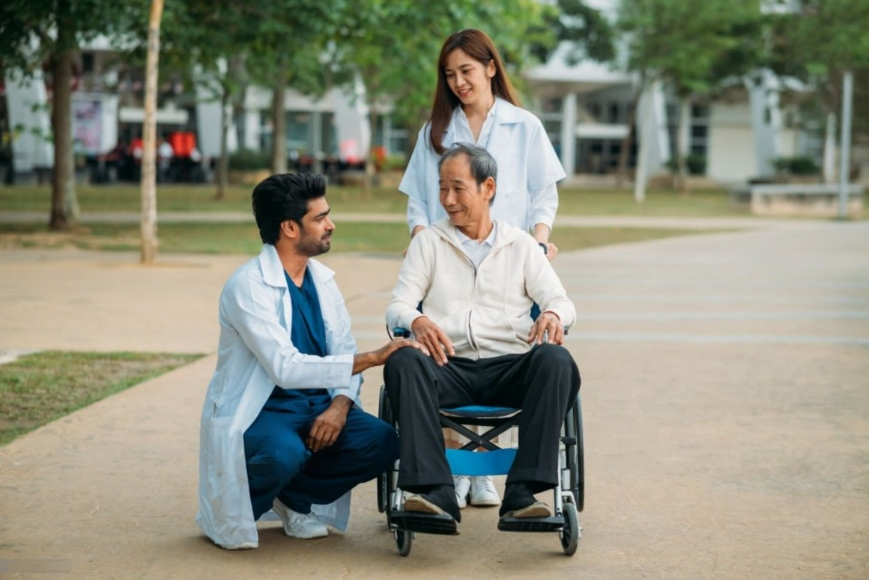 a cancer patient in a wheel chair being pushed by a women and a doctor.