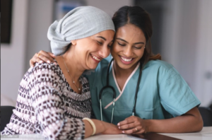 A cancer patient and a doctor smile as they look at something on a table.