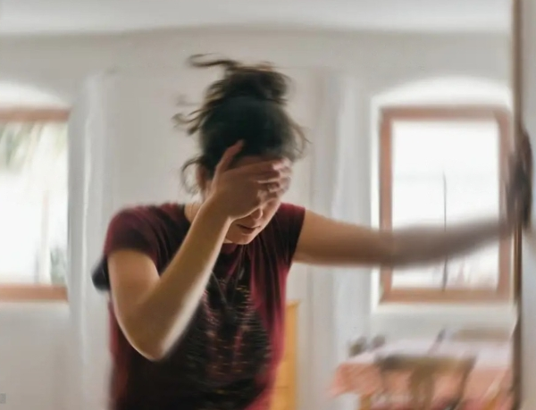 a woman standing in front of a mirror holding her forehead.