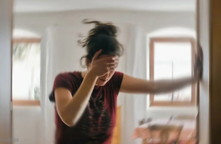 a woman standing in front of a mirror holding her forehead.