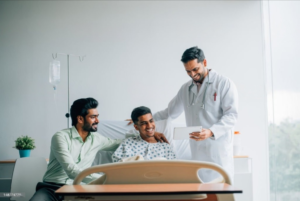 A group of men standing around a hospital bed at V Care Cancer Centre.